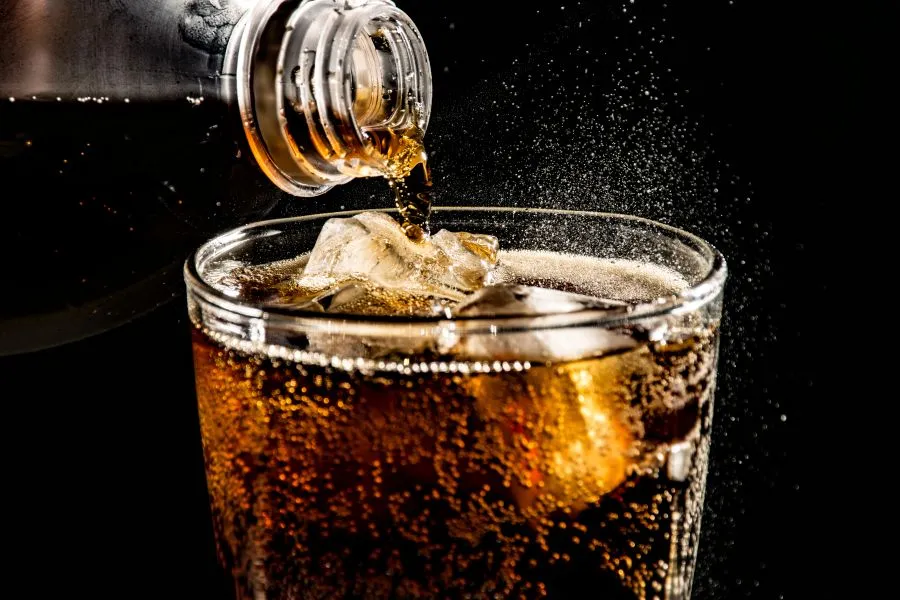 person pouring soda into glass